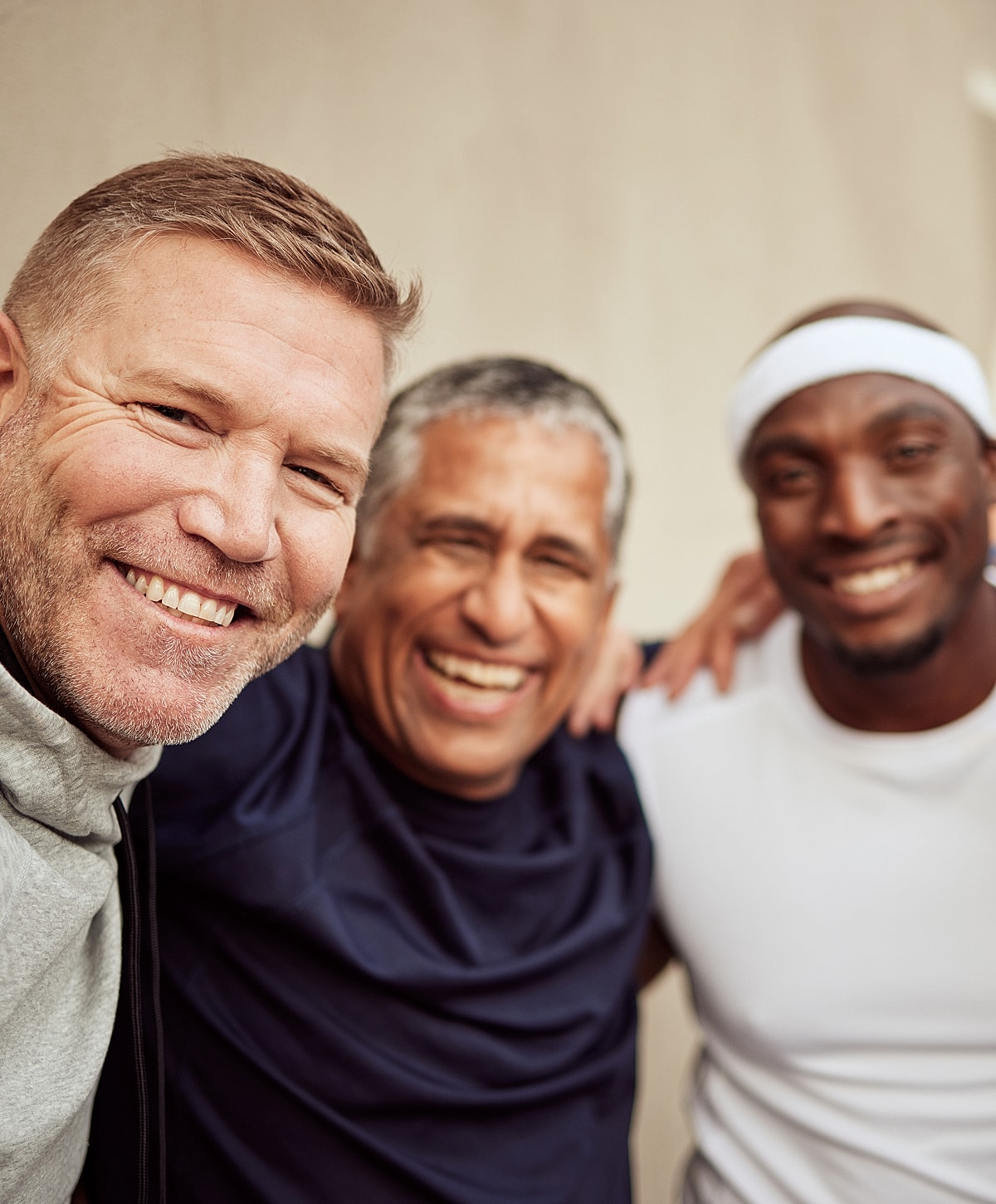 Three smiling men posing together happily.