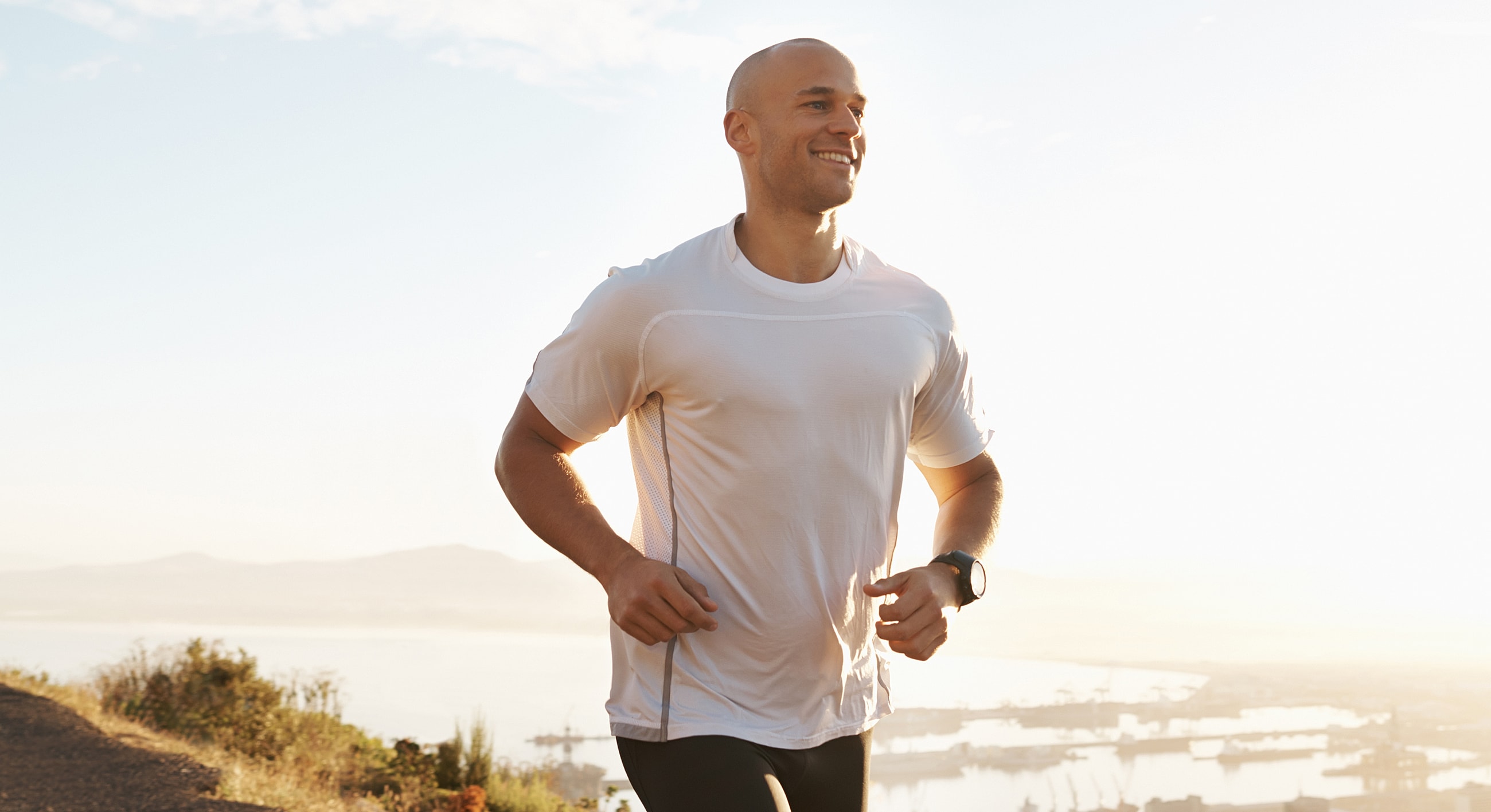 Man jogging outdoors with a scenic background.
